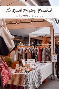 an outdoor market with clothes on display and people looking at items in the store window