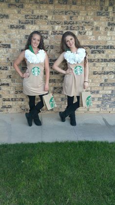 two girls dressed in starbucks outfits standing next to a brick wall