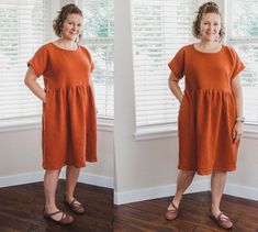 a woman standing in front of a window with her hands on her hips and wearing an orange dress