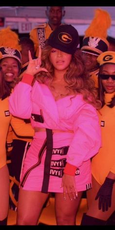 a group of women in pink outfits standing next to each other with one woman giving the peace sign