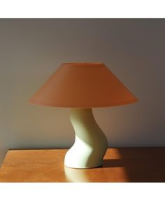 a table lamp sitting on top of a wooden table next to a white and beige wall