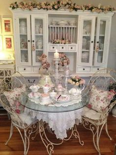 a dining room table with chairs and china cabinet in the corner, decorated with pink flowers