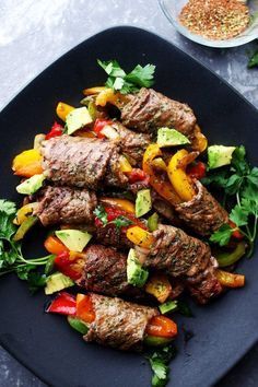 a black plate topped with meat and veggies