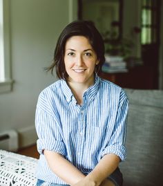 a woman sitting on a couch smiling at the camera