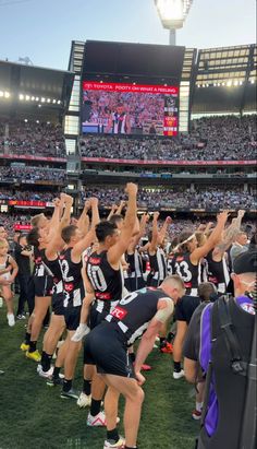 a group of people standing on top of a field holding hands up in the air