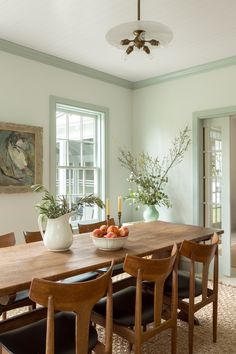 a dining room table with chairs and a bowl of fruit on top of the table