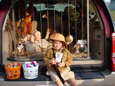 a little boy sitting in the back of a truck holding a stuffed animal and smiling