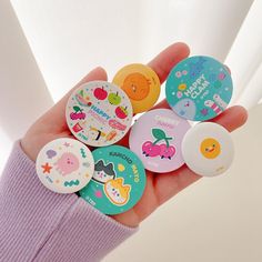 a person holding several different colored buttons in their hand with the words hello kitty on them