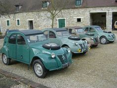 several old fashioned cars parked in front of a stone building