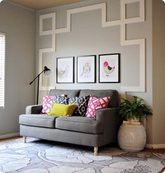 a living room with gray couches and pictures on the wall