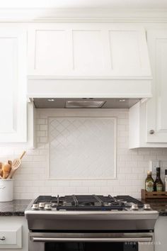 a stove top oven sitting inside of a kitchen next to white cabinets and counter tops