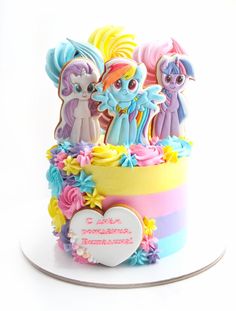 there is a cake decorated with little ponys and rainbow colored frosting on it