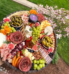 a platter filled with assorted meats, cheeses and vegetables next to flowers