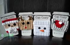 four crocheted coffee cups decorated like santa claus and snowmen