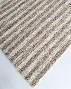 a close up of a rug on the floor with white and brown stripes in it