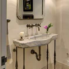 a bathroom sink sitting under a mirror next to a wall mounted faucet with flowers on it