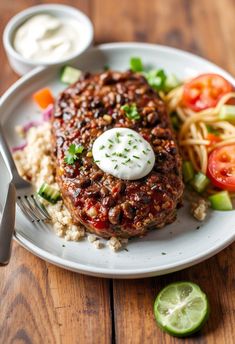 a white plate topped with meat, rice and veggies next to a fork