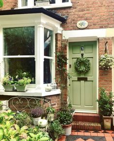 a green front door with potted plants in the window sill next to it