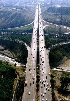 an aerial view of a highway with cars on it and the road to the city below