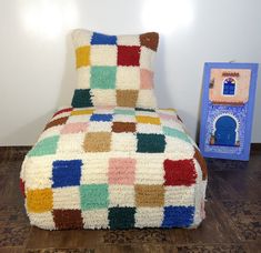 a multicolored blanket sitting on top of a wooden floor next to a chair