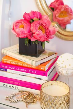 a stack of books sitting on top of a table next to a vase filled with flowers