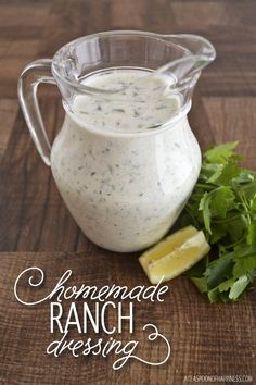 homemade ranch dressing in a glass pitcher with parsley and lemon wedges on the side