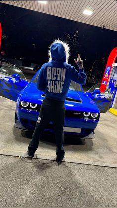 a person in a blue hoodie standing next to a car