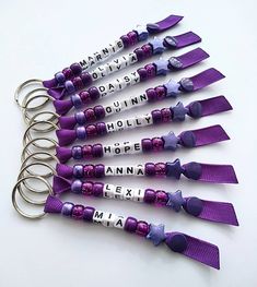 six purple and white key chains with words on them, all tied up to each other