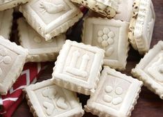 some white square shaped cookies sitting on top of a wooden table next to a red and white ribbon