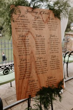 a wooden table plan with greenery on it sitting in front of a metal fence