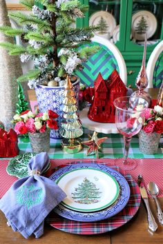 a table set for christmas with plates, napkins and silverware on top of it