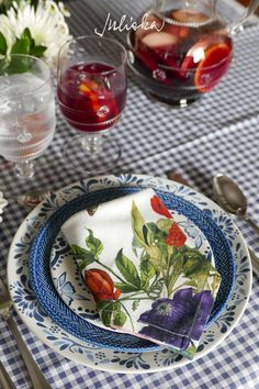 a blue and white plate with flowers on it next to wine glasses, spoons and utensils