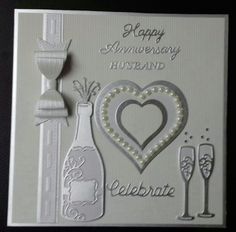 an anniversary card with two champagne glasses and a heart in the middle, on a table