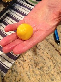 a person's hand holding an orange in front of a counter top with other items on it