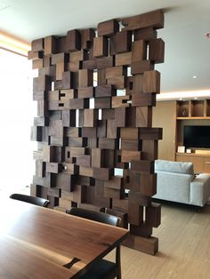 a room divider made out of wood blocks with chairs around it and a couch in the background