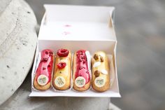 three hot dogs with toppings are in a box on the ground next to a statue