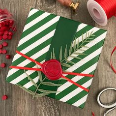 a green and white wrapping paper with a red wax stamp sitting on top of it