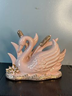 a pink swan figurine sitting on top of a wooden table