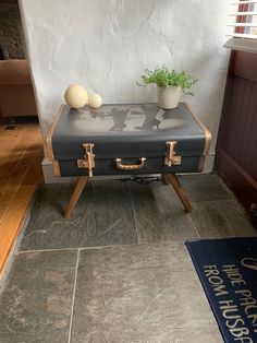 a suitcase sitting on top of a wooden table next to a potted green plant