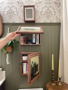 a bathroom with green walls and wooden shelves on the wall next to a white toilet