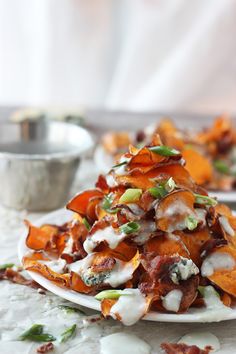 a pile of food sitting on top of a white plate next to a silver bowl