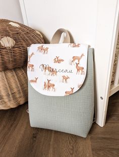 a purse with deer on it sitting next to a basket and wicker basket in the background