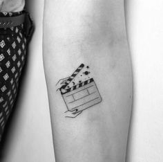 a black and white photo of a movie clapper tattoo on the left inner arm