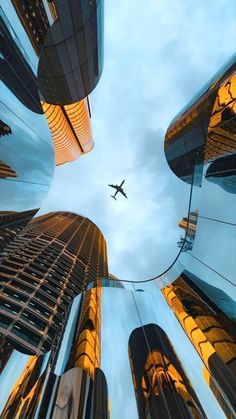 an airplane is flying through the sky between tall buildings