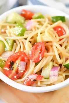 a white bowl filled with pasta and veggies on top of a wooden cutting board