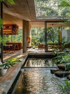 the inside of a house with water and plants in it's center area, surrounded by greenery