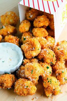 the fried food is ready to be eaten with dipping sauce on the side and in a paper box