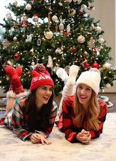 two women laying on the floor in front of a christmas tree