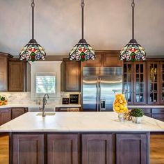 a kitchen with three lights hanging from the ceiling and an island in front of it