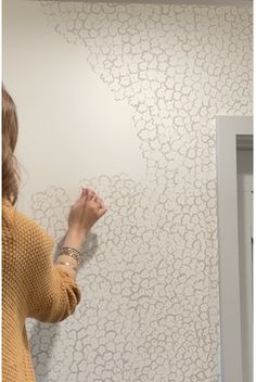 a woman is painting a wall with white paint and she has her hand on the wall